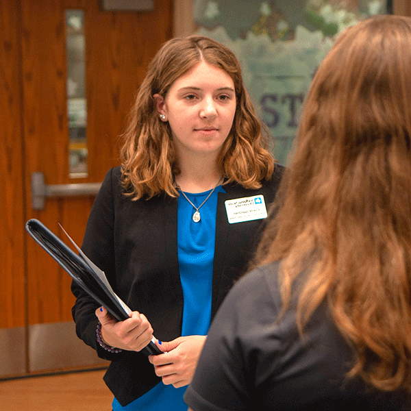 Two women talking while in professional attire.